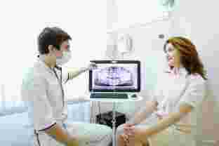 стоматолог обсуждает с пациентом рентгеновский снимок